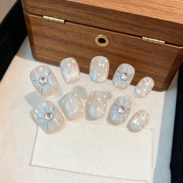 Blue press on nails with winter cat eye and snowflake design. Short, reusable fake nails for holiday or daily wear. Ice blue with silver sparkles.
